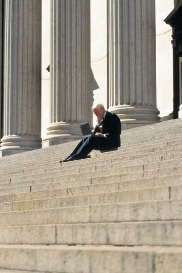 Mature male on laptop on imposing steps Mature male on laptop on imposing steps with columns in background