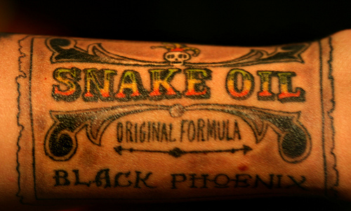 Photo of a multi-colored tatoo that reads "snake oil."
