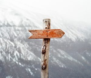 a wooden sign post in front of snowy mountains