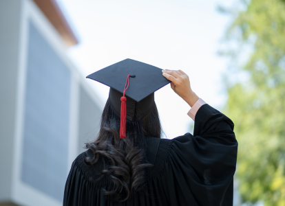 Photo of a student wearing graduation regalia taken from behind the student.