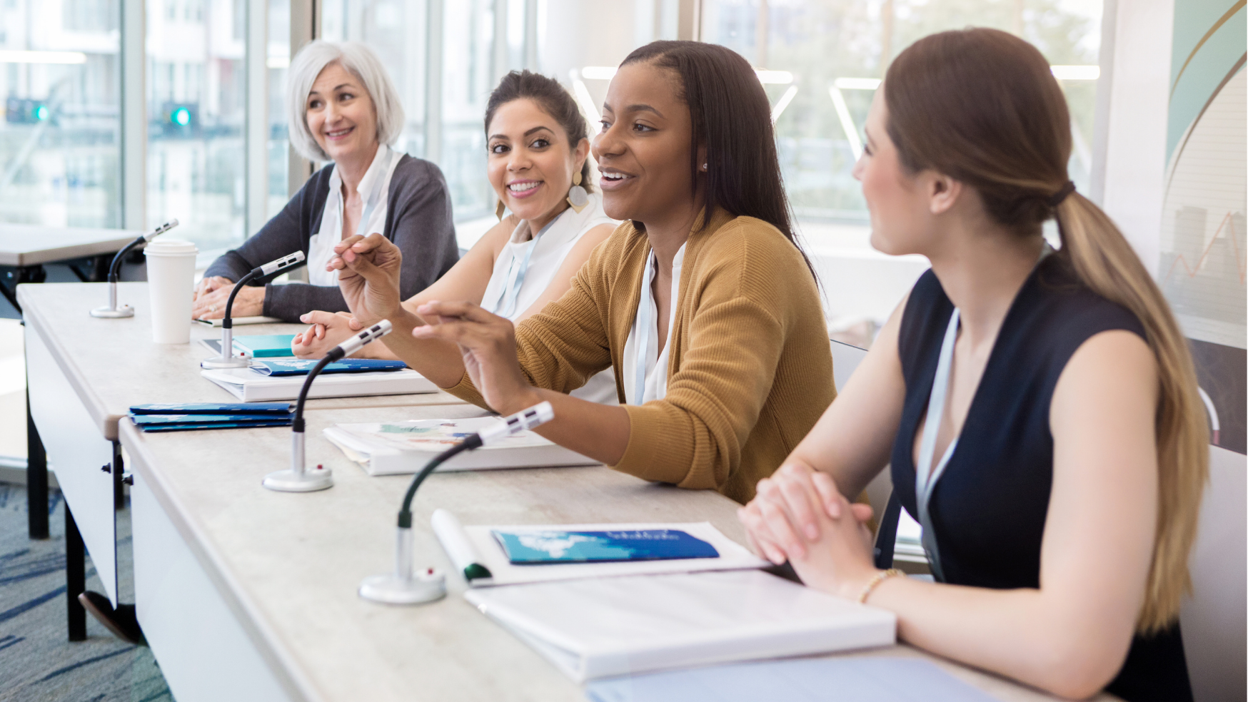 Four professionally dressed women speaking in a panel session format