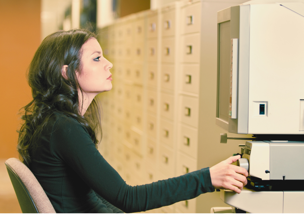 A woman using a microfilm reader.
